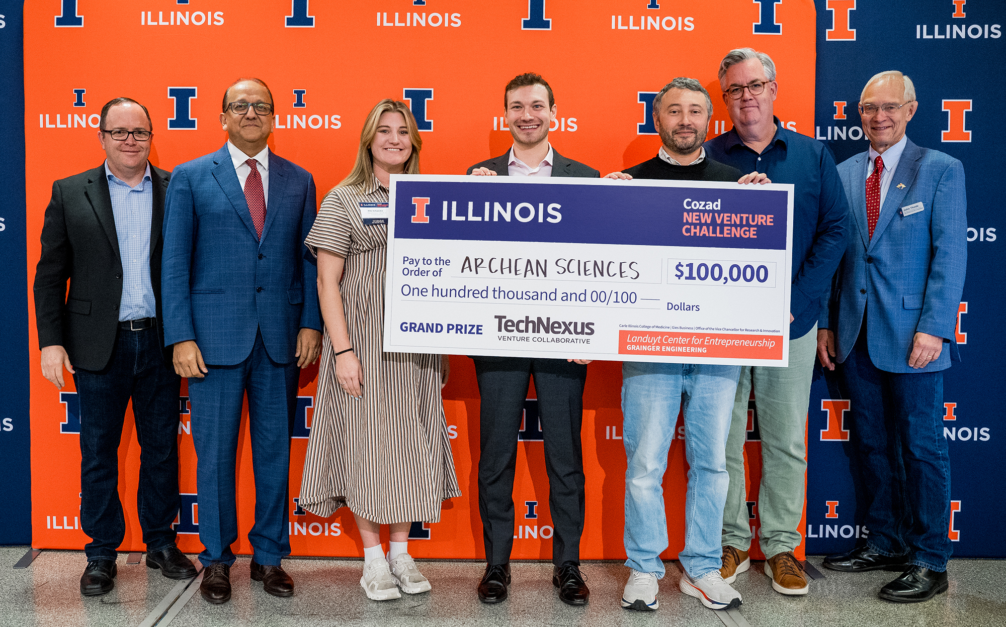 Grand prize winning team members holding a check of $100,000 with campus leadership and prize sponsors.